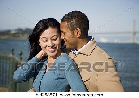 Stock Image - Couple hugging at waterfront. Fotosearch