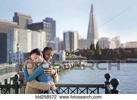Stock Image - Couple hugging at waterfront. Fotosearch