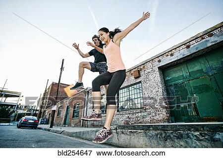 Stock Photo - Couple jumping off loading dock. Fotosearch