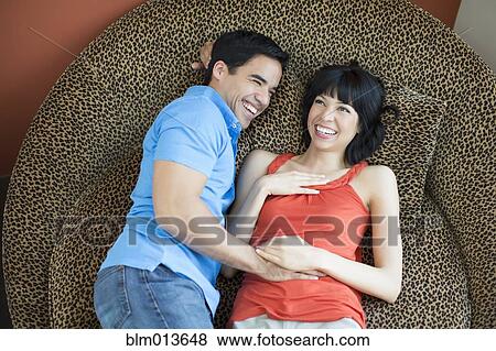 Stock Photo - Couple laying on modern chair. Fotosearch