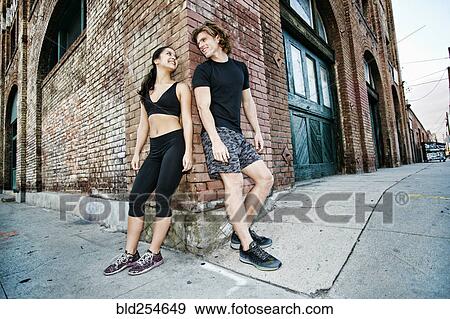 Couple leaning on corner of brick building View Large Photo Image Stock Photo - Couple leaning on corner of brick building. Fotosearch