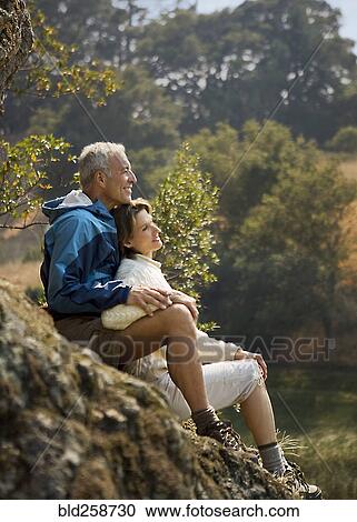 Stock Image - Couple sitting on rocks and relaxing. Fotosearch