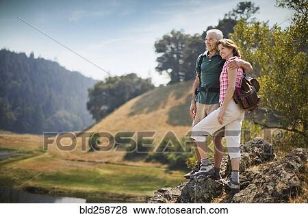 Couple standing on rocks admiring river View Large Photo Image Stock Photo - Couple standing on rocks admiring river. Fotosearch