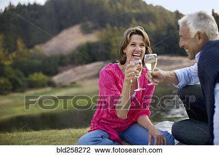 Stock Image - Couple toasting with wine and laughing. Fotosearch