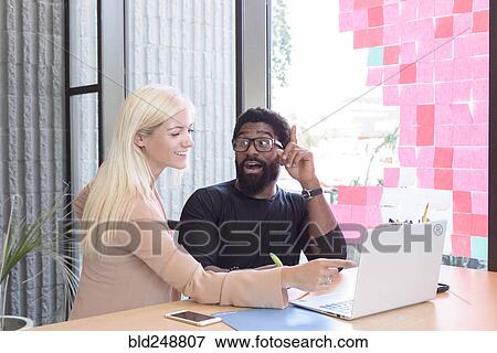 Creative business people using laptop at table View Large Photo Image Stock Photo - Creative business people using laptop at table. Fotosearch
