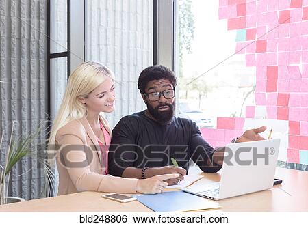 Stock Photograph - Creative business people using laptop at table. Fotosearch