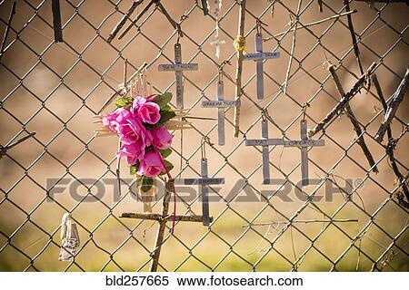 Stock Photography - Crucifixes and flowers hanging on memorial fence. Fotosearch