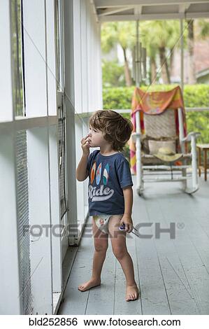 Stock Photograph - Curious Caucasian boy wearing diaper near screen door. Fotosearch