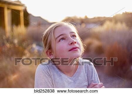 Stock Photo - Curious Caucasian girl looking up outdoors. Fotosearch
