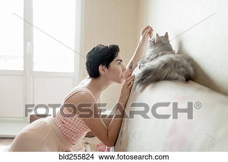 Curious Caucasian woman admiring cat on sofa View Large Photo Image Picture - Curious Caucasian woman admiring cat on sofa. Fotosearch