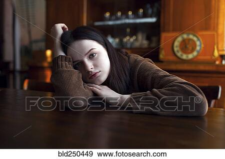 Stock Photo - Depressed Caucasian girl leaning on table. Fotosearch