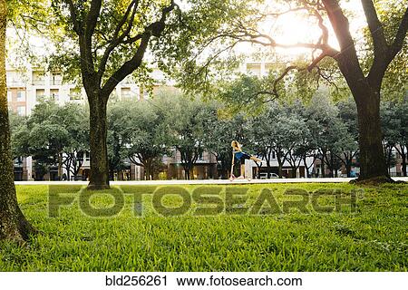 Distant Caucasian girl riding scooter in park View Large Photo Image Stock Image - Distant Caucasian girl riding scooter in park. Fotosearch