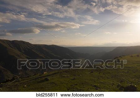 Stock Image - Distant Caucasian man admiring scenic view of valley. Fotosearch