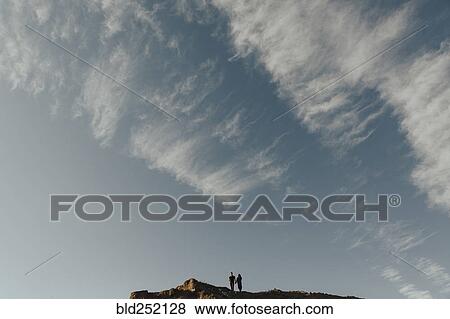 Stock Photo - Distant Middle Eastern couple under cloudy sky. Fotosearch