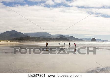 Stock Image - Distant people running on beach. Fotosearch