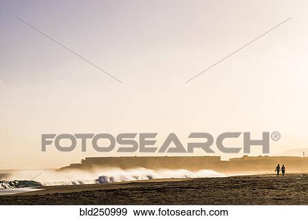 Stock Photo - Distant people walking on beach. Fotosearch