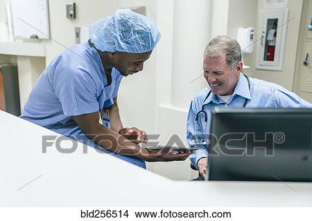 Picture - Doctor and nurse discussing digital tablet. Fotosearch