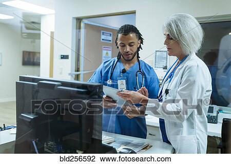 Stock Image - Doctor and nurse discussing digital tablet. Fotosearch