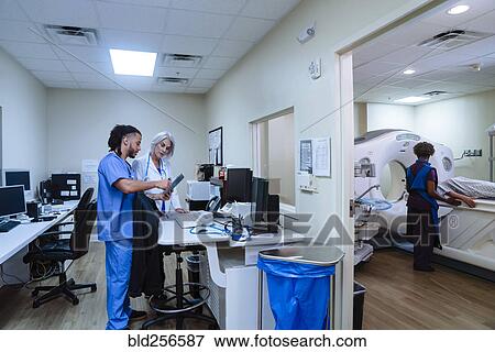 Stock Photo - Doctor and nurse discussing digital tablet near scanner. Fotosearch