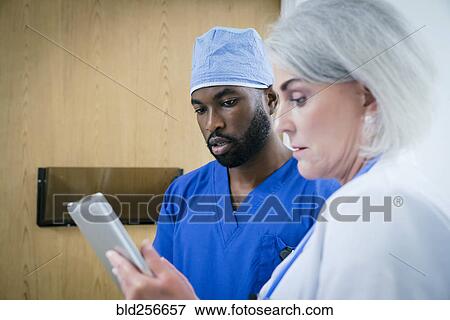 Stock Photo - Doctor and nurse discussing digital tablet. Fotosearch