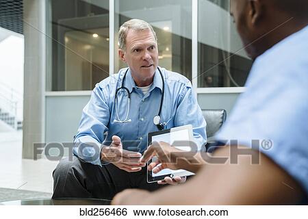 Stock Photograph - Doctor and nurse discussing digital tablet. Fotosearch