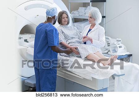 Stock Image - Doctor and nurse helping patient at scanner. Fotosearch