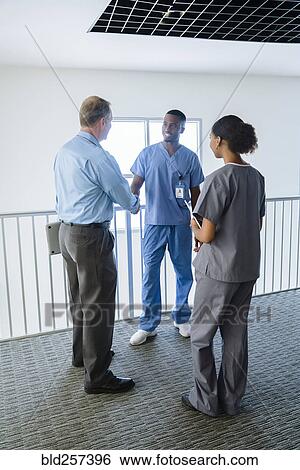 Doctor and nurse shaking hands near railing View Large Photo Image Stock Photograph - Doctor and nurse shaking hands near railing. Fotosearch