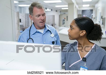 Stock Image - Doctor and nurse talking near computer. Fotosearch