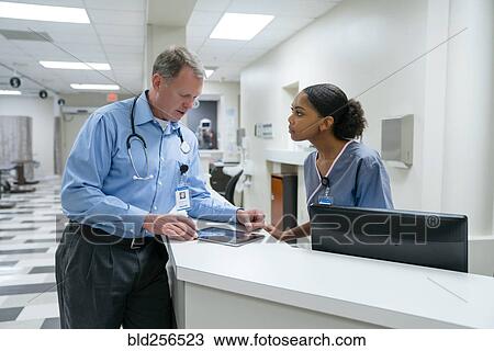 Stock Image - Doctor and nurse using digital tablet. Fotosearch