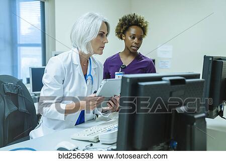 Stock Photo - Doctor and nurse using digital tablet and computer. Fotosearch