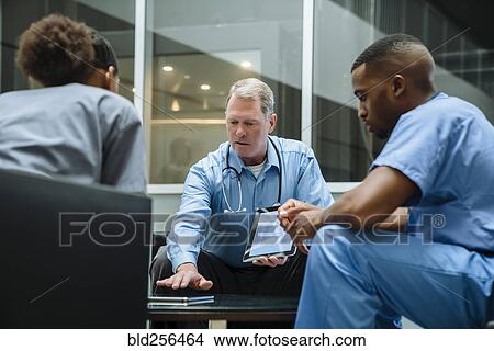 Picture - Doctor and nurses discussing digital tablet. Fotosearch