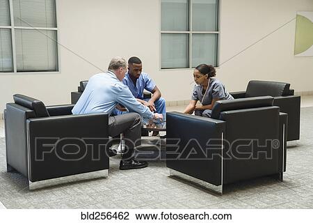 Stock Image - Doctor and nurses discussing digital tablet. Fotosearch