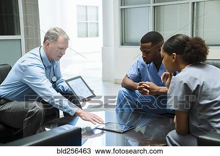 Stock Image - Doctor and nurses discussing digital tablet. Fotosearch