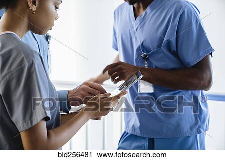 Stock Image - Doctor and nurses discussing digital tablet. Fotosearch