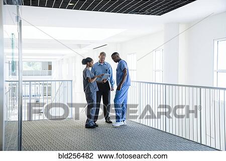 Stock Image - Doctor and nurses discussing digital tablet. Fotosearch