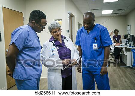 Stock Image - Doctor and nurses discussing digital tablet. Fotosearch