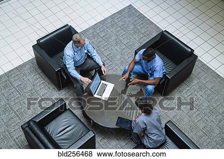 Stock Photo - Doctor and nurses discussing laptop. Fotosearch
