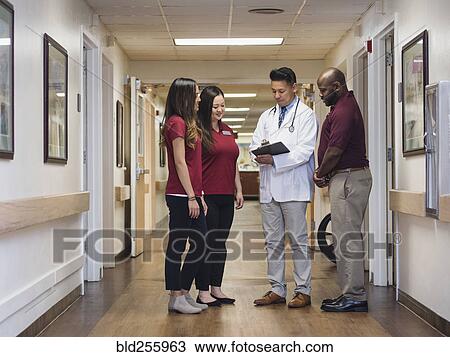 Doctor and nurses reading clipboard in hospital corridor View Large Photo Image Stock Image - Doctor and nurses reading clipboard in hospital corridor. Fotosearch