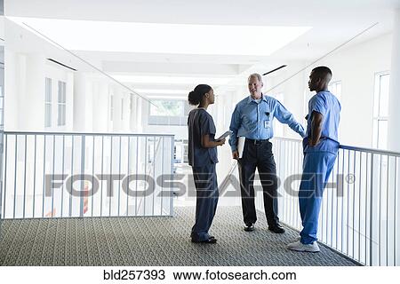Stock Image - Doctor and nurses talking near staircase. Fotosearch