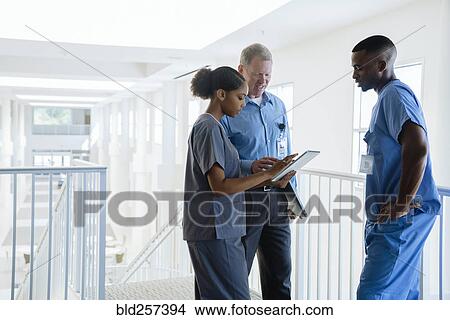 Picture - Doctor and nurses using digital tablet near staircase. Fotosearch