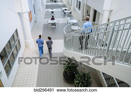 Stock Image - Doctor and nurses walking in lobby. Fotosearch