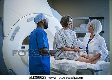 Stock Image - Doctor and technician talking to patient at scanner. Fotosearch