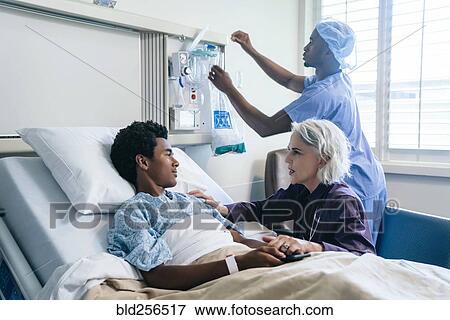 Stock Photo - Doctor comforting boy laying in hospital bed. Fotosearch
