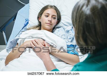 Stock Photo - Doctor comforting Caucasian girl laying in hospital bed. Fotosearch