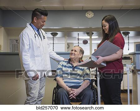 Stock Image - Doctor comforting patient in wheelchair. Fotosearch