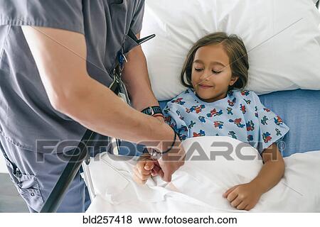 Stock Photo - Doctor holding hand of girl in hospital bed. Fotosearch