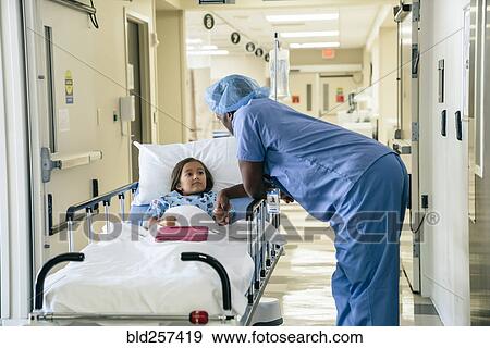 Stock Photo - Doctor holding hand of girl in hospital gurney. Fotosearch