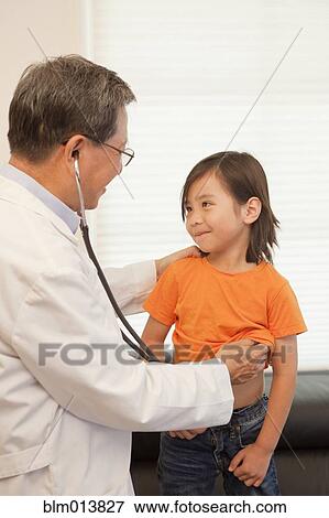 Stock Photo - Doctor listening to boy's breathing in clinic. Fotosearch