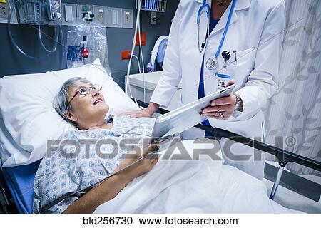 Stock Image - Doctor showing digital tablet to patient. Fotosearch