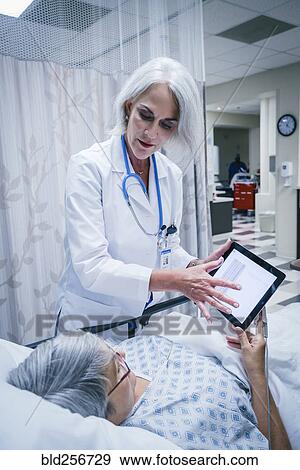 Doctor showing digital tablet to patient View Large Photo Image Stock Photo - Doctor showing digital tablet to patient. Fotosearch